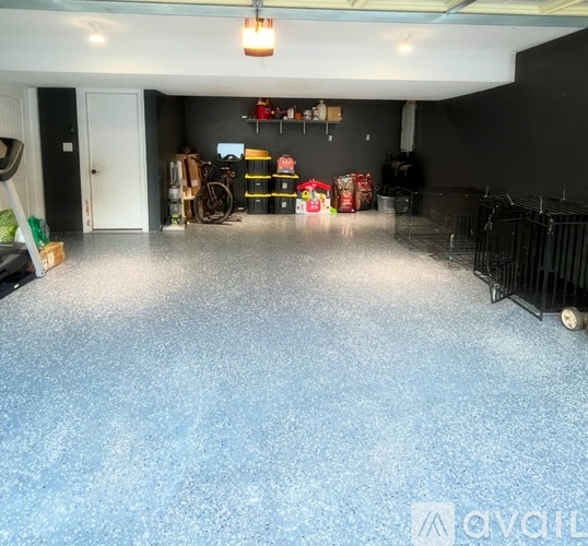 A spacious garage with a blue floor and various items stored on the shelves.