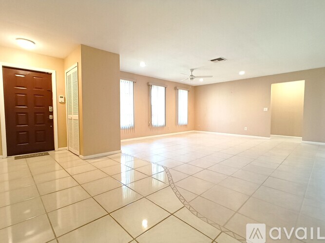 A spacious room with a tiled floor and a ceiling fan.