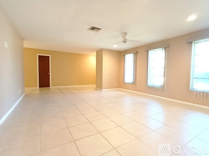 Empty room with a ceiling fan and three windows.