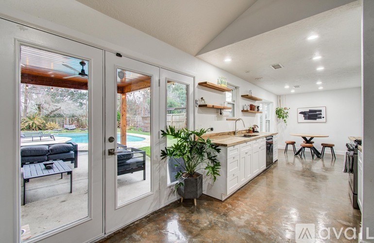 A kitchen with a dining table and chairs is visible through a glass door.
