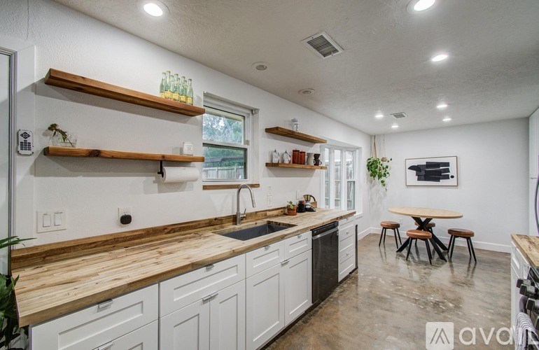 A kitchen with white cabinets and wooden countertops.