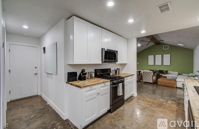 A kitchen with white cabinets and a wooden countertop.