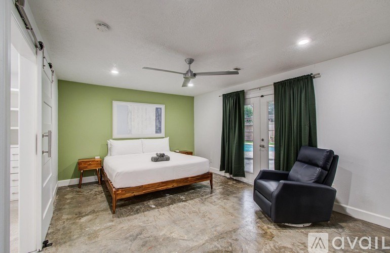 A bedroom with a bed, chair, and a fan.