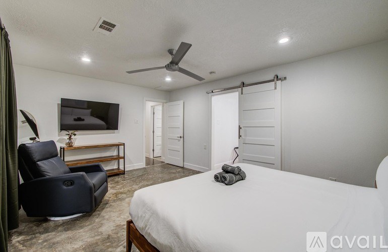 A bedroom with a bed, chair, and sliding door.
