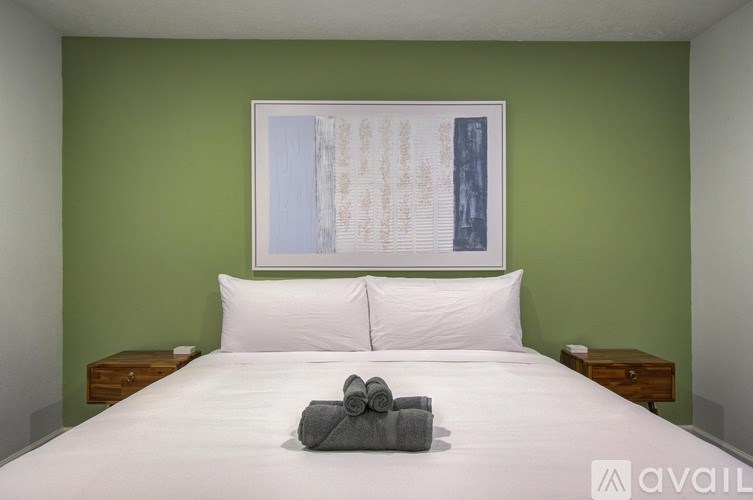 A bed with white pillows and a grey towel on top of it.