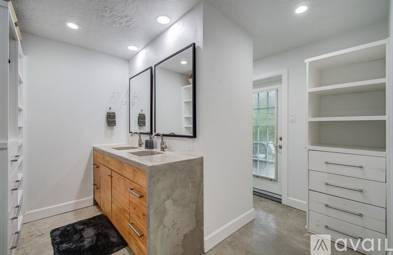 A bathroom with a sink, mirror, and a black rug on the floor.