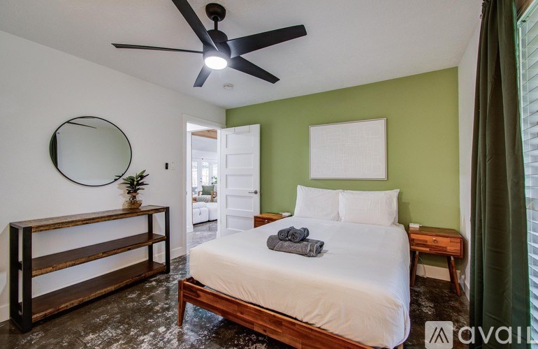 A bedroom with a bed, a mirror, and a wooden shelf.