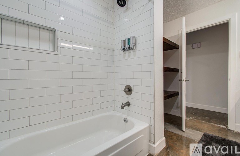 A white bathtub in a bathroom with a white tiled wall.