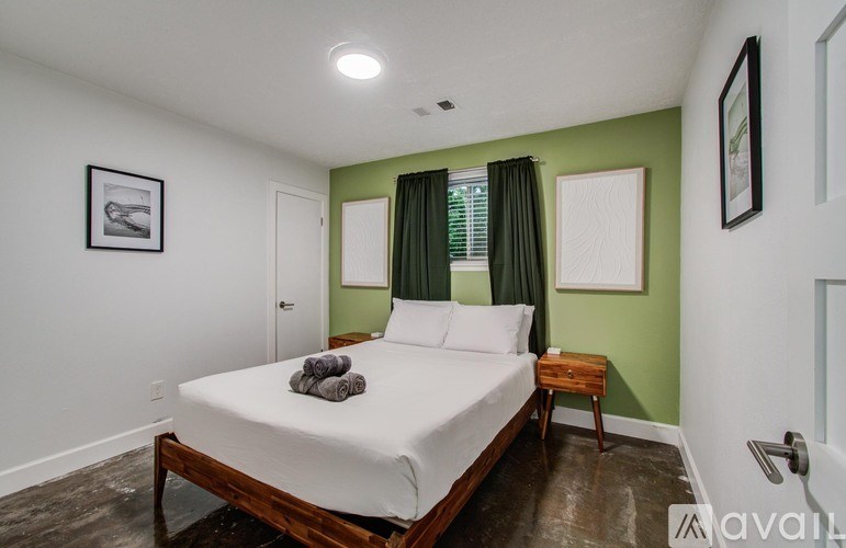 A bedroom with a bed, nightstand, and two pictures on the wall.