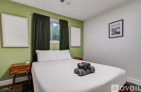 A bedroom with a white bed and a green wall.