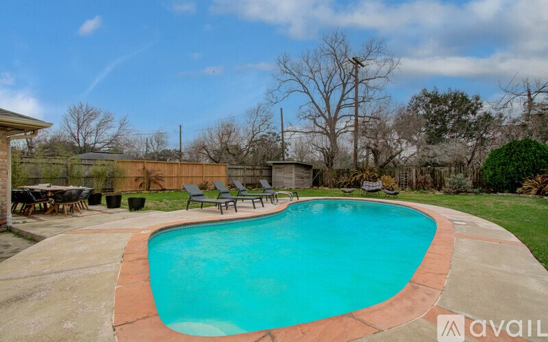 A swimming pool surrounded by a concrete patio and a wooden fence.