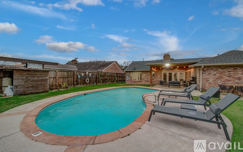 A backyard with a pool and lounge chairs.