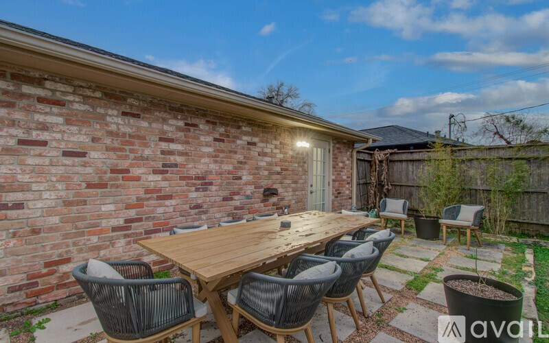 A wooden table is surrounded by chairs on a patio.