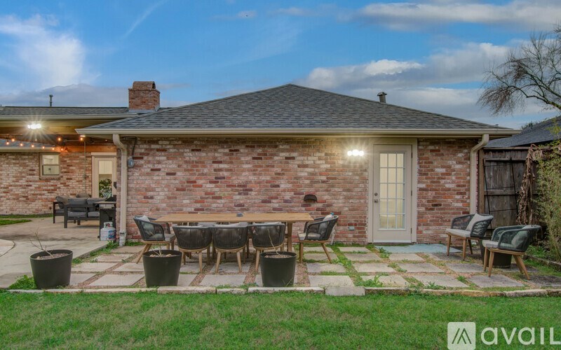 A house with a brick exterior and a patio with chairs and a table.
