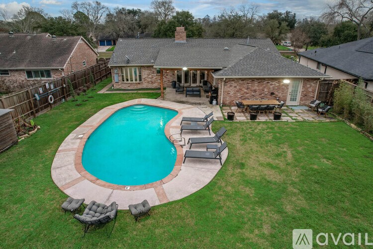 A backyard with a pool and patio furniture.