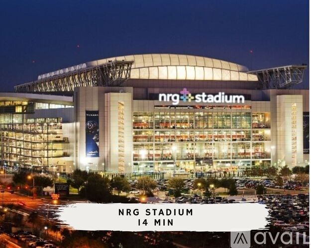 NRG Stadium is lit up at night with a parking lot in the foreground.