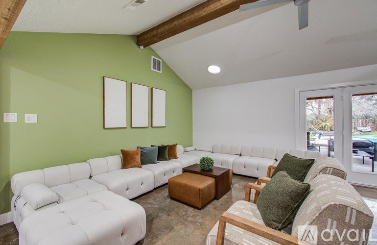 A living room with a white couch and a green wall.