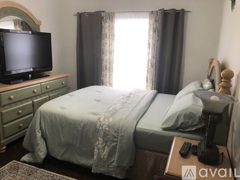 A bedroom with a large bed and a white furry rug on the floor.