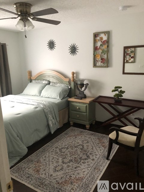 A bedroom with a bed, a chair, and a table with a plant on it.