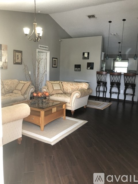 A living room with a sofa, a coffee table, and a chandelier.