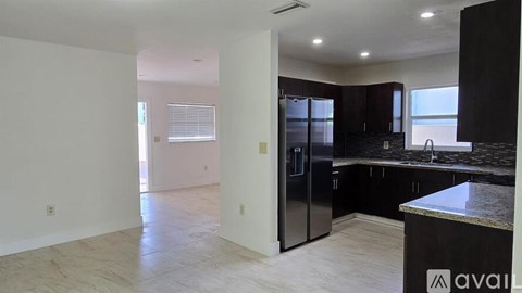 A kitchen with a black refrigerator and cabinets.