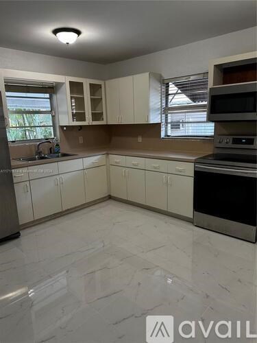 A kitchen with white cabinets and a marble floor.
