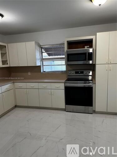 A kitchen with white cabinets and a marble floor.