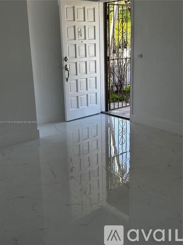 A white door with a glass window is in a room with white walls and a white floor.