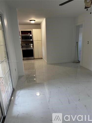 A spacious kitchen with white marble flooring and a ceiling fan.