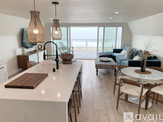 A modern kitchen with a large island and a view of the beach.