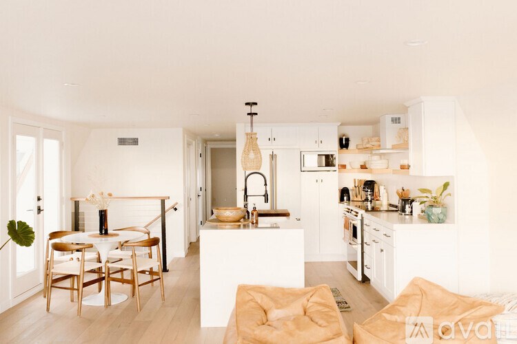A modern kitchen with white cabinets and a dining table with chairs.