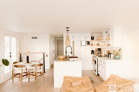 A modern kitchen with white cabinets and a dining table with chairs.