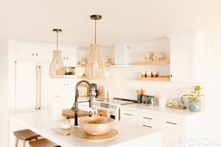 A kitchen with white cabinets and a white countertop with a wooden bowl on it.
