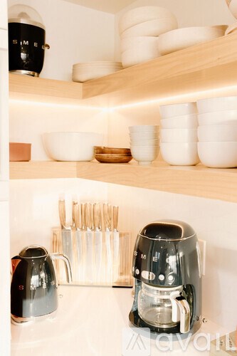 A kitchen with a coffee maker and a kettle on the counter.