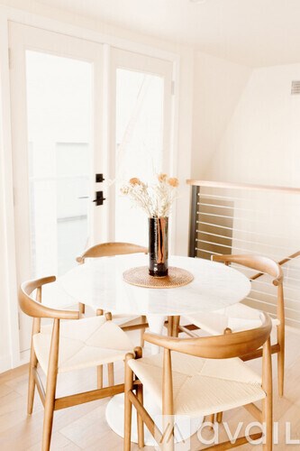 A table with chairs and a vase of flowers.