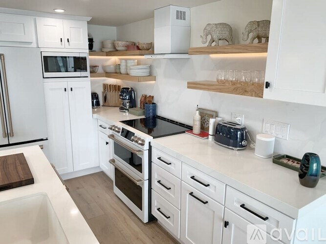 A kitchen with white appliances and wooden shelves.