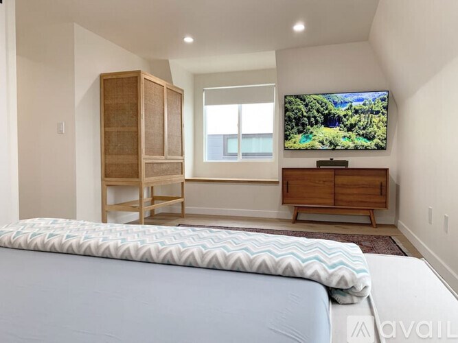 A bedroom with a bed, a TV, and a window.