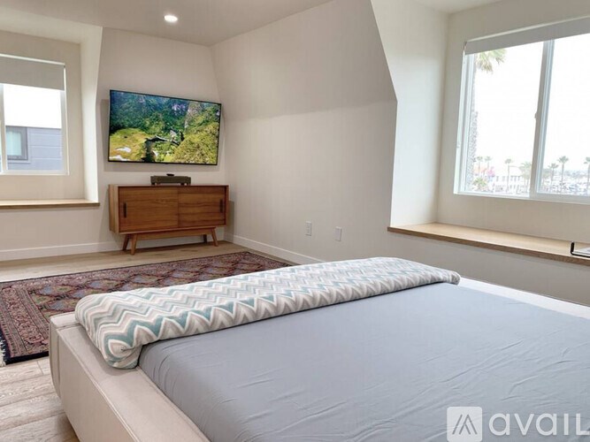 A bedroom with a large bed and a flat screen TV mounted on the wall.