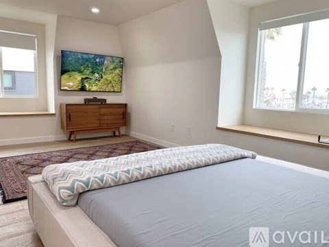 A bedroom with a large bed and a flat screen TV mounted on the wall.