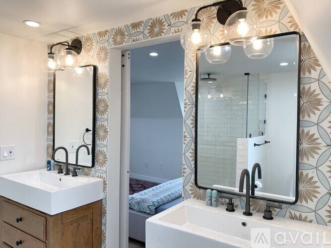 A bathroom with a sink, mirror, and lighting fixtures.