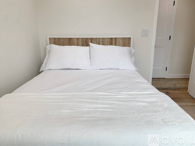 A white bed with a wooden headboard and two pillows.