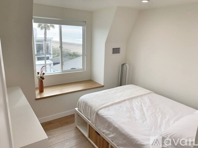 A bedroom with a large bed and a window overlooking the beach.