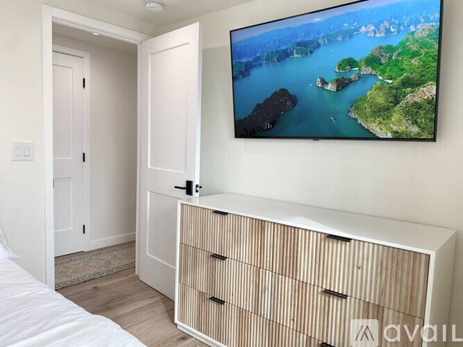 A bedroom with a large TV mounted on the wall displaying a scenic view.
