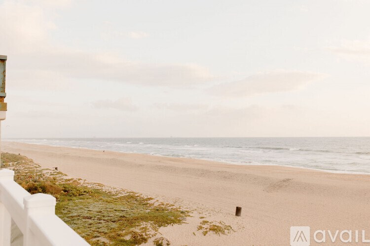 A beach scene with a white fence in the foreground.