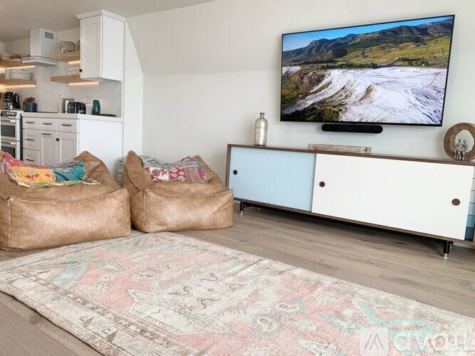 A living room with a television on the wall and two bean bag chairs in front of it.