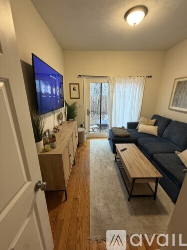 A living room with a blue couch and a flat screen TV mounted on the wall.
