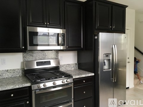 A kitchen with black cabinets and stainless steel appliances.
