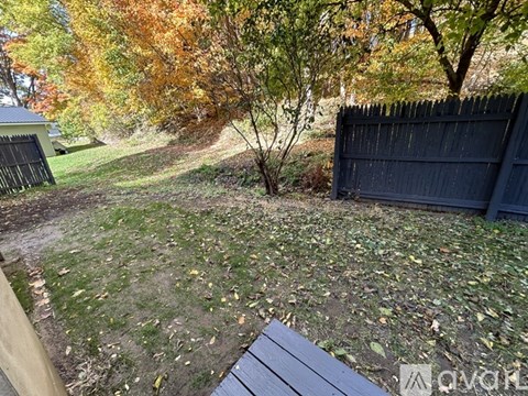 A backyard with a wooden bench and a fence.