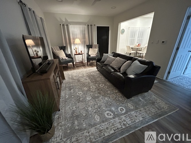A living room with a black couch and a rug with a pattern on it.