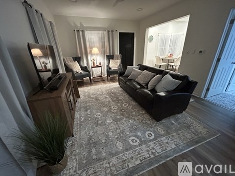 A living room with a black couch and a rug with a pattern on it.